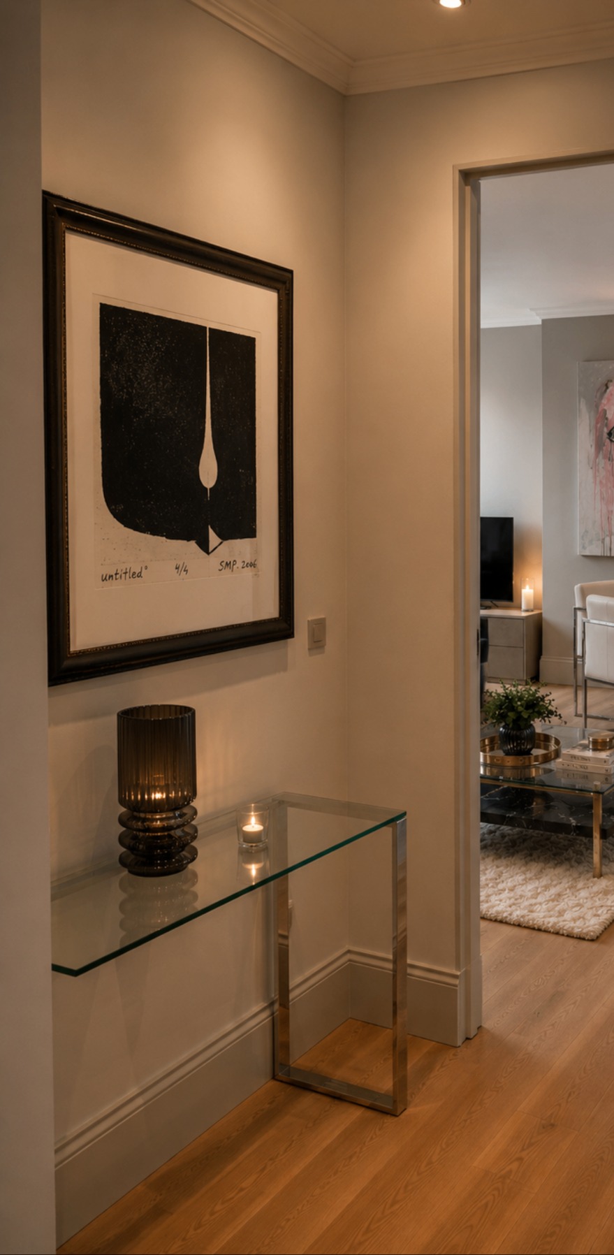 A framed print above a glass console in a hallway