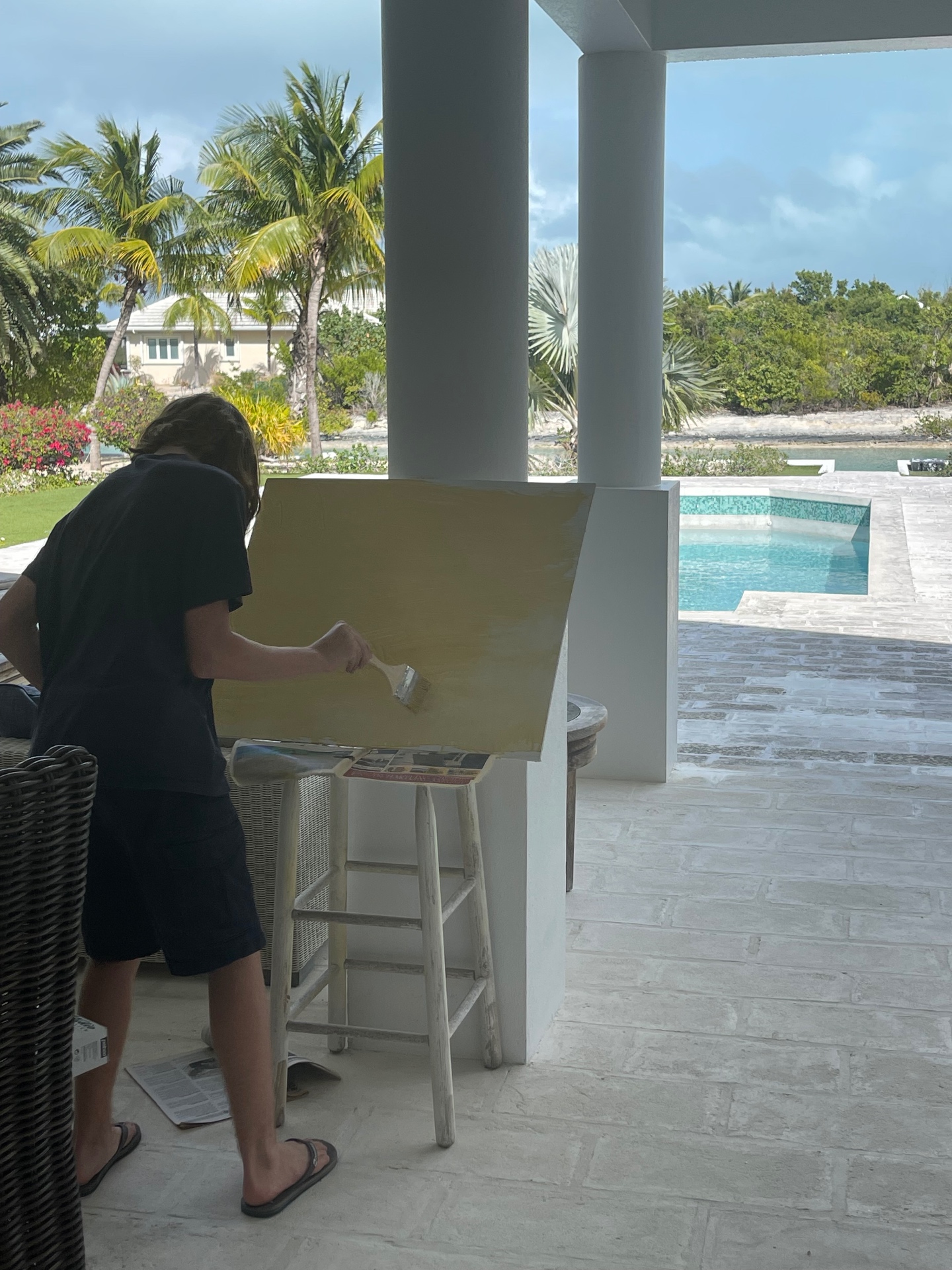 Student painting a large canvas beside a pool in Turks and Caicos