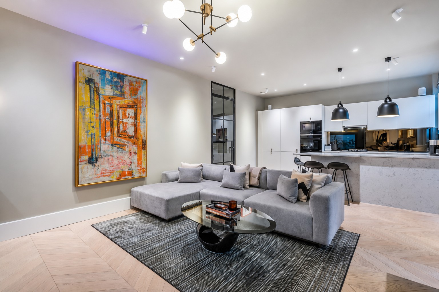 An orange and blue painting above a grey sofa in an open-plan living room
